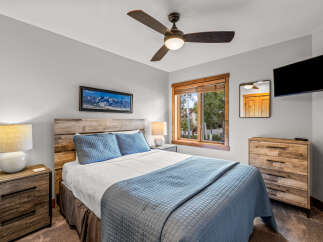 Experience ultimate comfort in this beautifully appointed bedroom, featuring a plush queen-size bed with crisp white linens and inviting blue quilted bedding.
