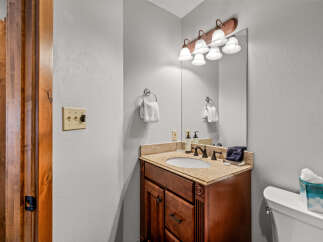 This bathroom features a warm and inviting aesthetic with its rich wood vanity and granite countertops.
