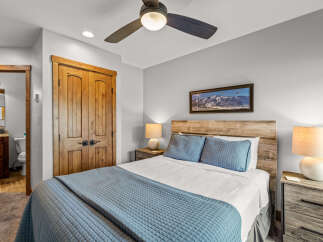 This cozy bedroom features a comfortable queen-size bed with crisp white linens and plush blue quilted bedding, perfect for a restful night's sleep.
