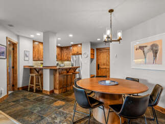 This inviting dining area features a warm wooden dining table with comfortable black leather chairs, perfect for family meals.