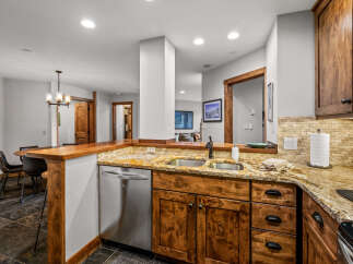 This kitchen boasts custom knotty pine cabinetry and a stunning granite countertop, complemented by a stone tile backsplash.