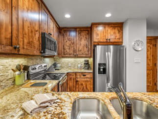 This stunning kitchen boasts custom wood cabinetry, granite countertops, and stainless steel appliances, creating a warm and inviting atmosphere.