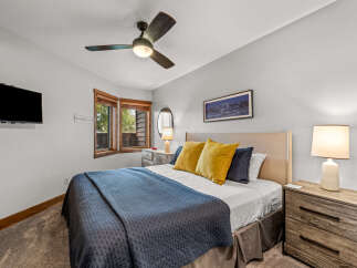 Experience ultimate comfort in this inviting bedroom, featuring a plush queen-size bed adorned with a stylish navy quilt and accent pillows.