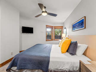 Experience comfort and style in this inviting bedroom, featuring a plush bed adorned with vibrant yellow and navy accent pillows.