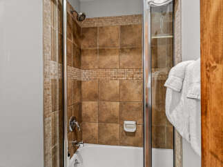 Step into this beautifully appointed bathroom featuring a tiled shower with a built-in soap dish and a sleek chrome showerhead.
