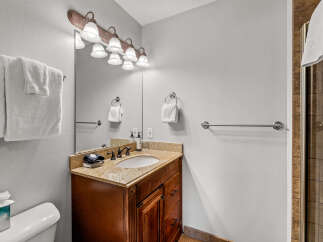 This bathroom features a beautiful wooden vanity with a granite countertop and a white undermount sink.