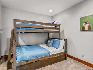 This cozy bedroom features a sturdy wooden bunk bed with blue quilted bedding, perfect for accommodating guests or children.