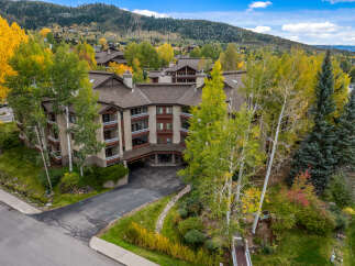 Experience the beauty of autumn in this stunning mountain property, featuring a multi-story building nestled amongst vibrant fall foliage.