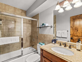 This bathroom features a spacious bathtub with a sliding glass door and a convenient showerhead.
