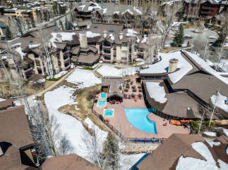 Experience luxury mountain living with this stunning aerial view of a resort-style property featuring a sparkling blue swimming pool and multiple hot tubs.