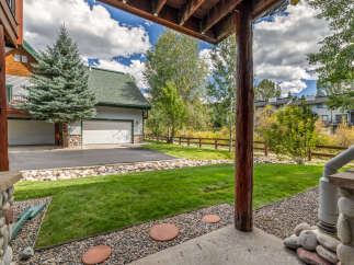 Enjoy the outdoors from this covered patio, overlooking a lush green lawn and a picturesque wooden fence.