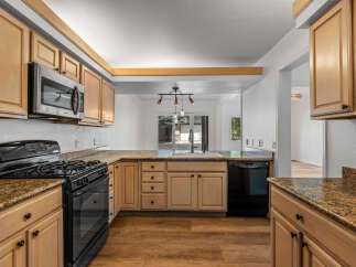 Discover this charming kitchen featuring light wood cabinetry and granite countertops, perfect for meal preparation.