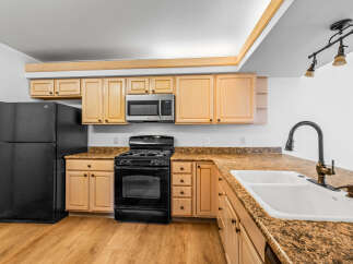 This kitchen boasts light wood cabinetry complemented by granite countertops, offering a warm and inviting atmosphere.