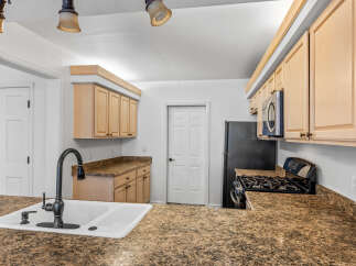 This kitchen features light wood cabinetry and granite countertops, offering a warm and inviting atmosphere.
