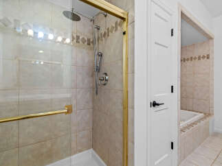 Step into this elegant bathroom featuring a spacious glass-enclosed shower with a rainfall showerhead and a handheld wand for a luxurious bathing experience.