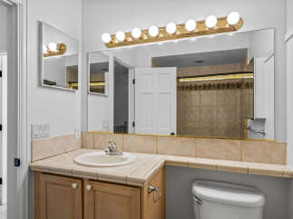 This bathroom features a light wood vanity with a tiled countertop and a white sink.