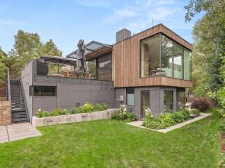 Experience modern luxury in this stunning home featuring a striking architectural design with natural wood and dark gray siding.