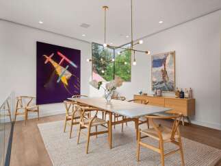 This modern dining room features a large wooden table surrounded by elegant wishbone chairs, all set on a textured jute rug.