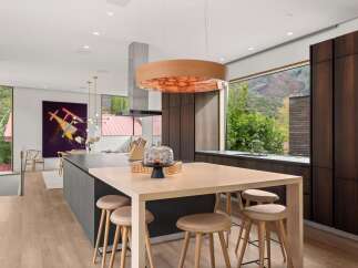 Experience luxury living in this modern kitchen, featuring a large island with seating and a stunning wood-paneled range hood.