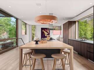 Experience modern luxury in this stunning kitchen, featuring a large wooden island with comfortable seating and a striking copper pendant light.