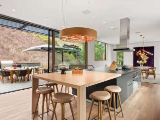 Experience seamless indoor-outdoor living in this modern kitchen, featuring a large island with bar seating and a sleek gas range.