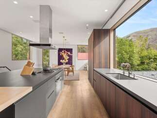 Experience modern luxury in this stunning kitchen, featuring sleek dark countertops and a prominent stainless steel range hood.