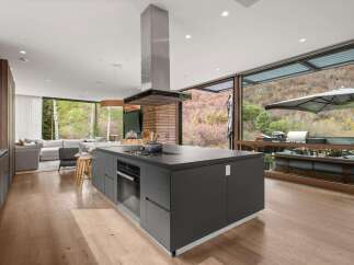 Experience luxury living in this modern open-concept kitchen, featuring a sleek dark gray island with a built-in gas range and oven.