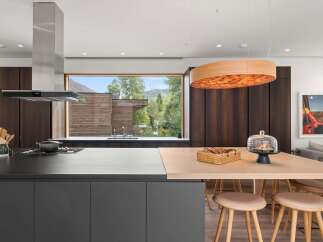 Experience luxury living in this modern kitchen featuring a sleek Miele range hood and dark wood cabinetry.