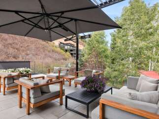 Experience luxurious outdoor living on this expansive patio, complete with a large umbrella for shade and comfortable seating arrangements.