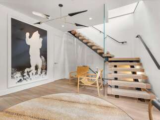 Step into a modern entryway featuring a striking black and white artwork of a bear, complemented by a unique multi-arm chandelier.