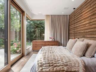 Experience luxurious comfort in this master bedroom, featuring a stunning wooden accent wall and a plush, textured throw blanket.