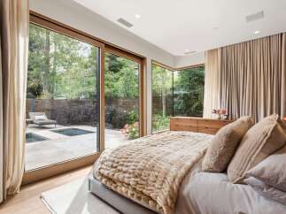 Experience luxurious indoor-outdoor living in this stunning bedroom, featuring expansive sliding glass doors that open to a private backyard oasis with a pool and spa.