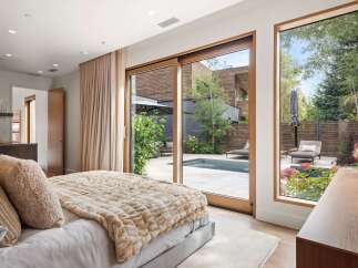 Experience luxurious indoor-outdoor living in this stunning bedroom, featuring a plush bed and direct access to a private backyard oasis.