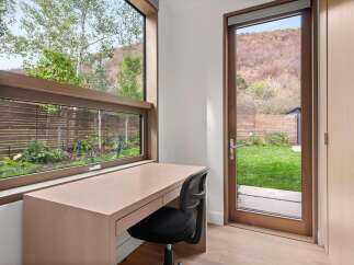This modern home office features a sleek, minimalist desk and a comfortable black office chair, perfectly positioned to enjoy the natural light and scenic views.