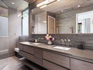Experience modern luxury in this stunning bathroom, featuring a sleek double vanity with minimalist faucets and a stone accent wall.