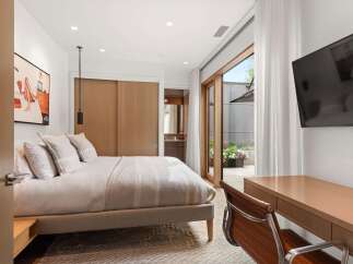 This modern bedroom features a comfortable king-size bed with plush pillows and a textured throw blanket, creating a cozy and inviting atmosphere.