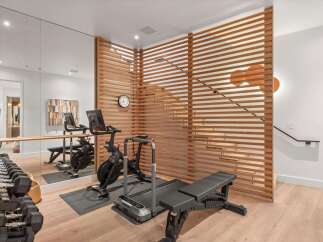 Elevate your fitness routine in this modern home gym, featuring a Peloton bike, treadmill, and weight bench.