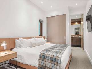 Experience luxury and comfort in this beautifully appointed bedroom, featuring a plush king-size bed with crisp white linens and a stylish plaid throw.