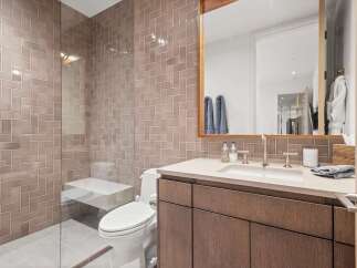 Experience modern luxury in this stunning bathroom, featuring a sleek vanity with a stone countertop and warm wood cabinetry.