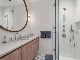 Experience modern luxury in this stunning bathroom, featuring a sleek vanity with a stone countertop and warm wood cabinetry.