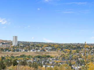 Experience breathtaking panoramic views from this stunning property, showcasing a vibrant cityscape nestled amidst rolling hills and autumn foliage.