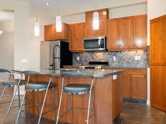 Experience modern living in this stunning kitchen, featuring sleek cherry wood cabinetry and a spacious island perfect for casual dining or entertaining.