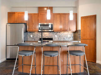 Experience modern living in this stunning kitchen, featuring sleek stainless steel appliances, including a refrigerator and microwave, complemented by rich cherry wood cabinetry.