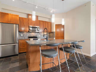 Experience modern living in this stunning kitchen, featuring sleek stainless steel appliances, rich wood cabinetry, and a spacious island perfect for entertaining.