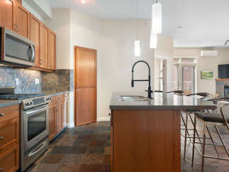This modern kitchen boasts sleek stainless steel appliances, including a microwave and oven, complemented by warm cherry wood cabinetry.