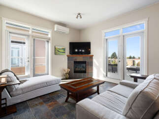 Experience modern living in this bright and airy living room, featuring a cozy fireplace and a large flat-screen TV perfect for entertainment.