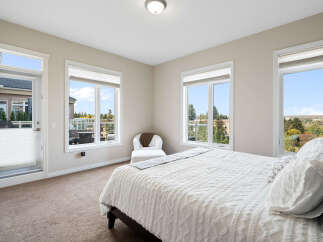 Experience comfort and style in this beautifully appointed bedroom, featuring a plush white comforter and a cozy armchair.