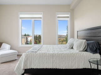 Experience comfort and style in this beautifully appointed bedroom, featuring a plush white duvet with intricate textured patterns and a dark wood headboard.