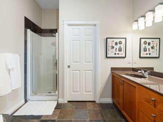 This spacious bathroom features a modern glass-enclosed shower with slate tile accents and a convenient towel rack.
