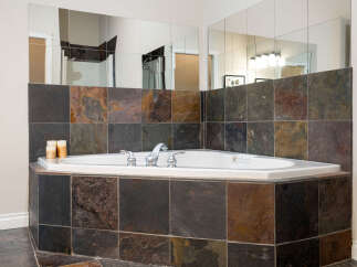 Indulge in relaxation with this luxurious corner bathtub, featuring a sleek chrome faucet and a tiled surround.